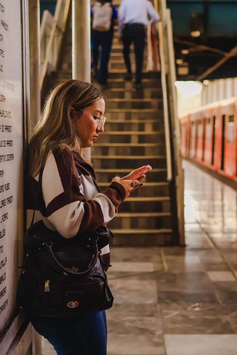 Una joven escribe en su teléfono mientras espera en el andén del Metro.