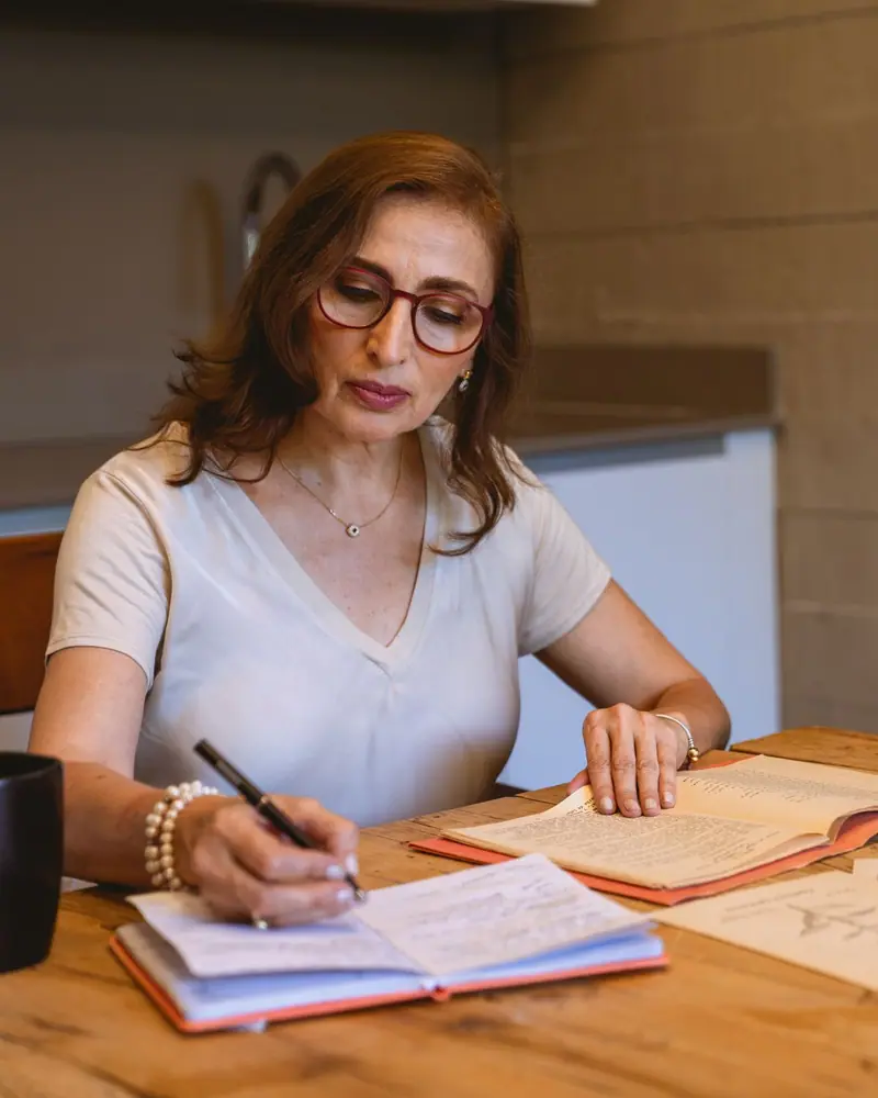 Una mujer anota en su libreta en la mesa de su cocina.