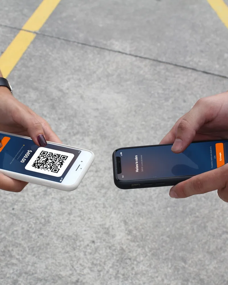 Dos manos juntan sus teléfonos: en uno, el QR de un Pendi por $450; en el otro, «Mariana te cobra» y el botón «Sí, lo acepto».